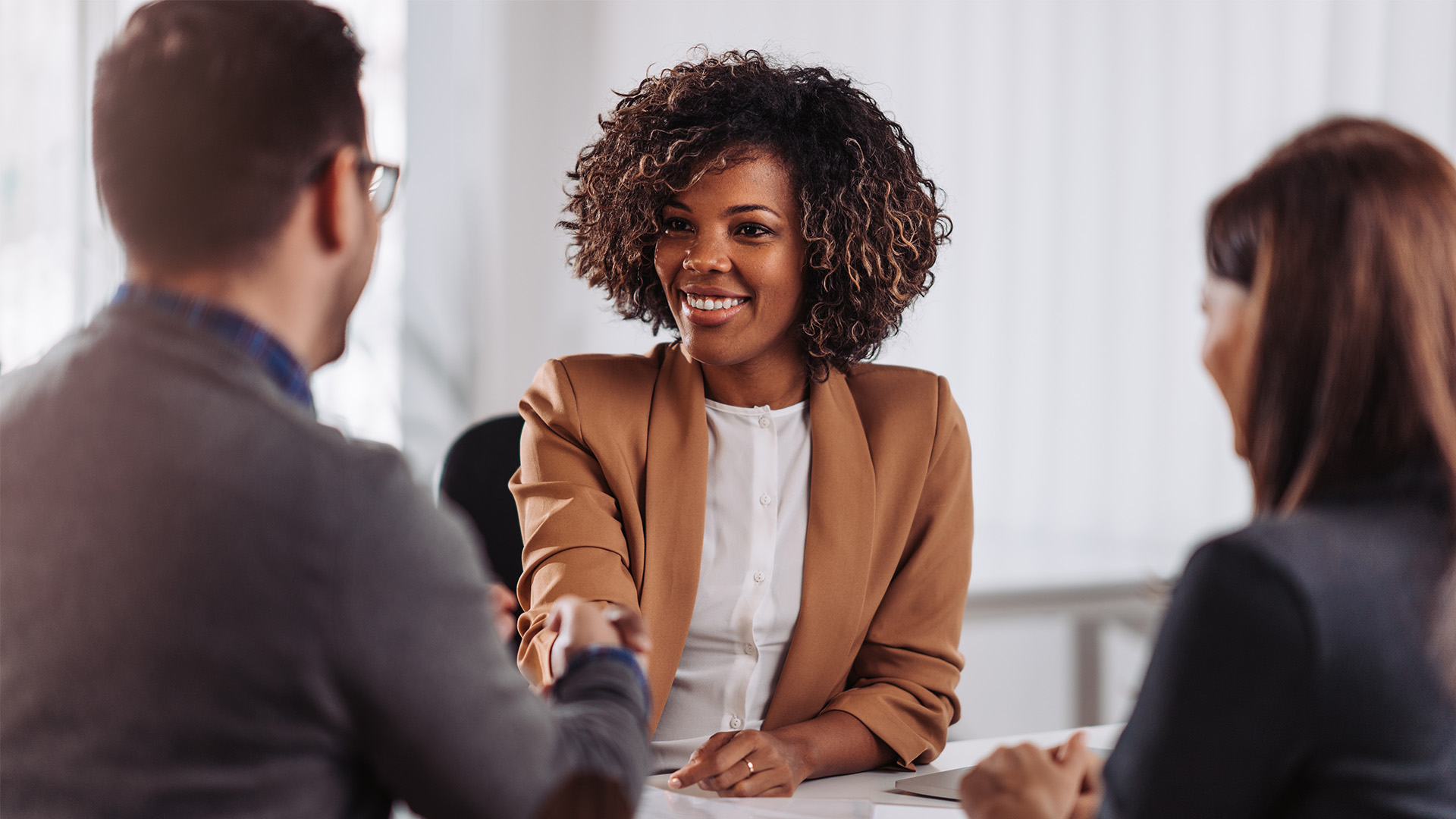 Three people seated in a business meeting.