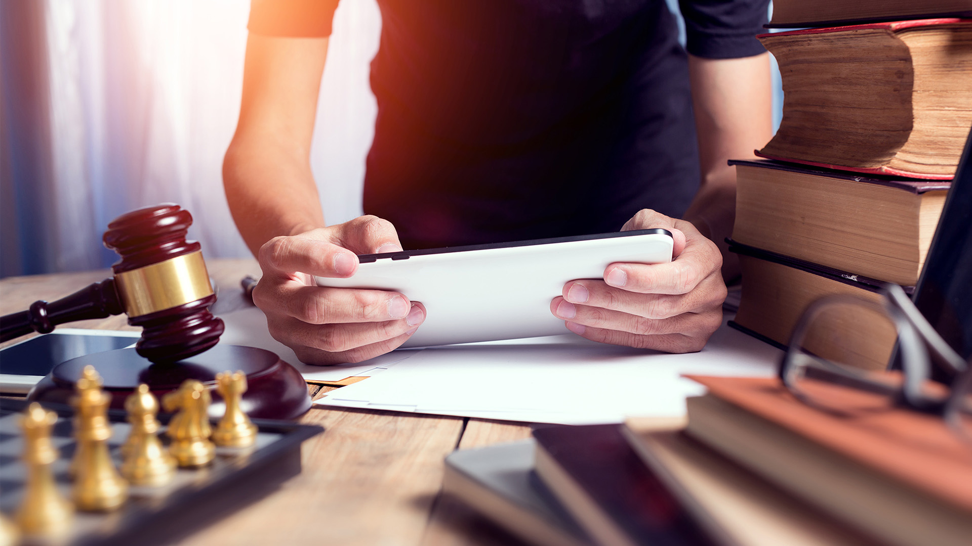 Person sitting at desk with books, chess board, and a gavel.