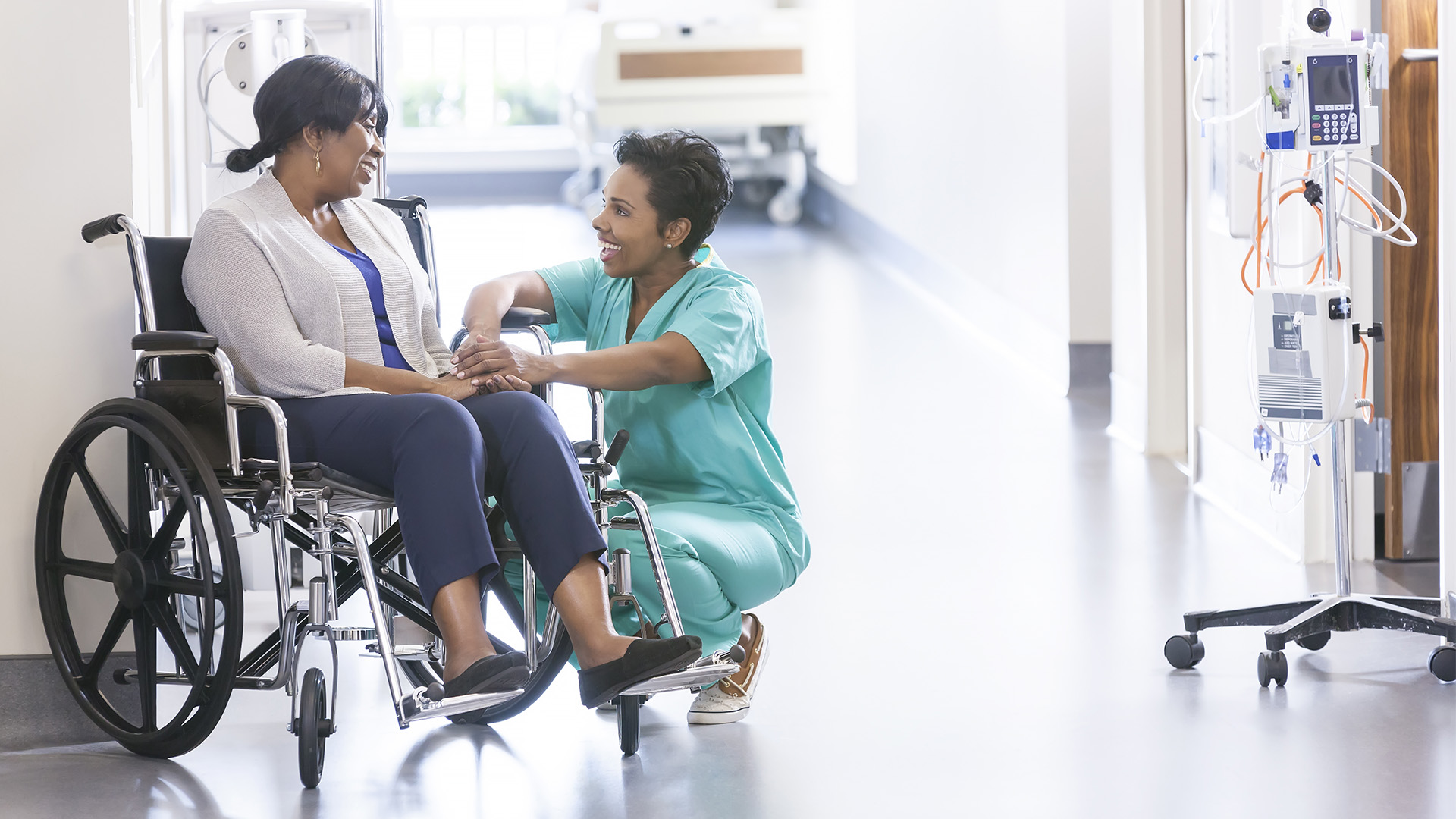 Nurse talking with a patient in a wheelchair.